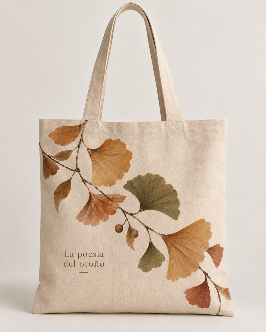 Tote bag color crema con hojas de ginkgo en tonos marrones y verdes y frase La poesía del otoño.